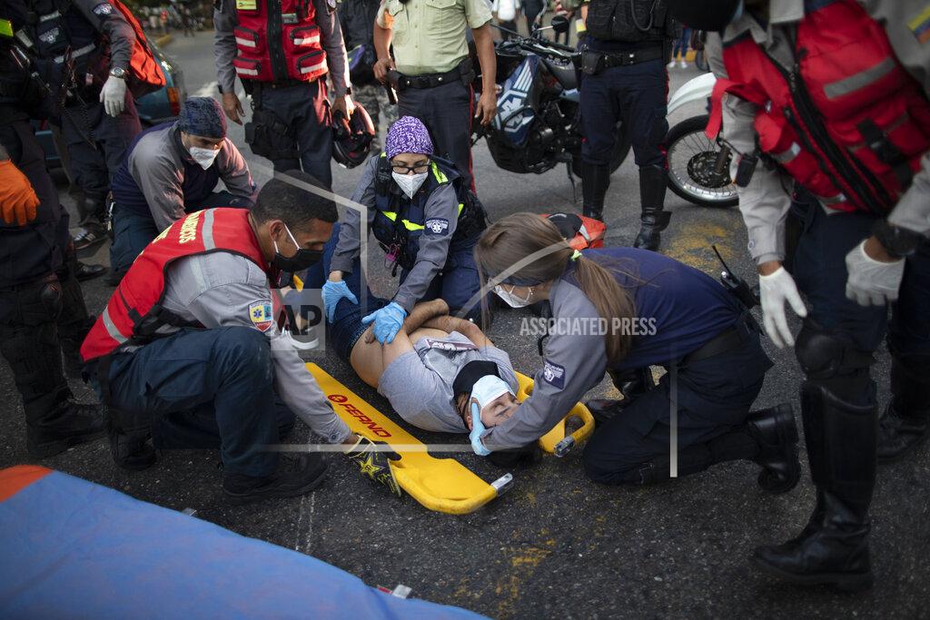 Ariana Cubillos Wearing masks as a precaution against the new coronavirus, Angels of the Road volunteer paramedics, in grey and blue uniforms, place a motorcycle accident victim onto a scoop stretcher, in Caracas, Venezuela, Monday, Feb. 8, 2021. According to the volunteers, most of their calls involve traffic accidents. (AP Photo/Ariana Cubillos)