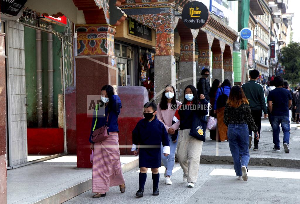 Uncredited Bhutanese people wearing face masks as precaution against coronavirus walk through a street in Thimpu, Bhutan, Monday, April 12, 2021. The tiny Himalayan kingdom wedged between India and China has vaccinated nearly 93% of its adult population since March 27. Overall, the country has vaccinated 62% of its 800,000 people. (AP Photo)