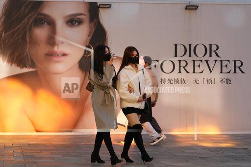 Women wearing masks walk past an ad for Dior at a mall in Beijing, China, Thursday, Nov. 25, 2021. A renowned Chinese fashion photographer has apologized for her past work after online critics called it insulting to the Chinese people and fashion house Dior removed one of her photos from a show in Shanghai. (AP Photo/Ng Han Guan)
