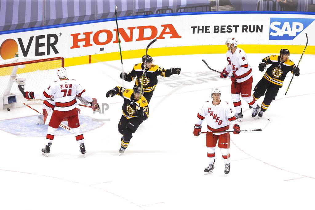 Chris Young Carolina Hurricanes' Brock McGinn (23) Dougie Hamilton (19) and Jaccob Slavin (74) react as Boston Bruins' Patrice Bergeron (37), Jake DeBrusk (74) and Brad Marchand (63) celebrate David Krejci's goal during the first period of an NHL Eastern Conference Stanley Cup hockey playoff game in Toronto, Thursday, Aug. 13, 2020. (Chris Young/The Canadian Press via AP)