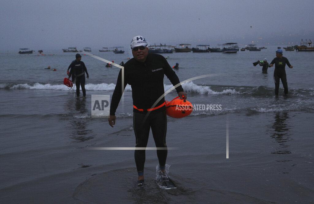 Martin Mejia Open water swimmers walk backwards in their flippers, into the sea from Pescadores beach where swimming in the ocean is booming while pools are closed due to the COVID-19 pandemic in Lima, Peru, at sunrise Tuesday, April 27, 2021. One of the few sporting disciplines that have been maintained during the coronavirus pandemic is swimming, which due to the closure of the swimming pools, has moved to the open sea. (AP Photo/Martin Mejia)