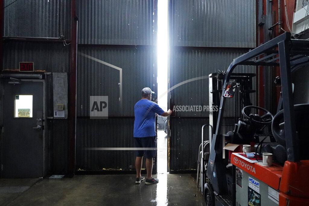 Gerald Herbert Jarod Voisin closes the doors of his family's heavily damaged oyster processing plant, as rain from Tropical Storm Nicholas, currently in the Gulf of Mexico, comes down, in the aftermath of Hurricane Ida in Houma, La., Tuesday, Sept. 14, 2021. (AP Photo/Gerald Herbert)