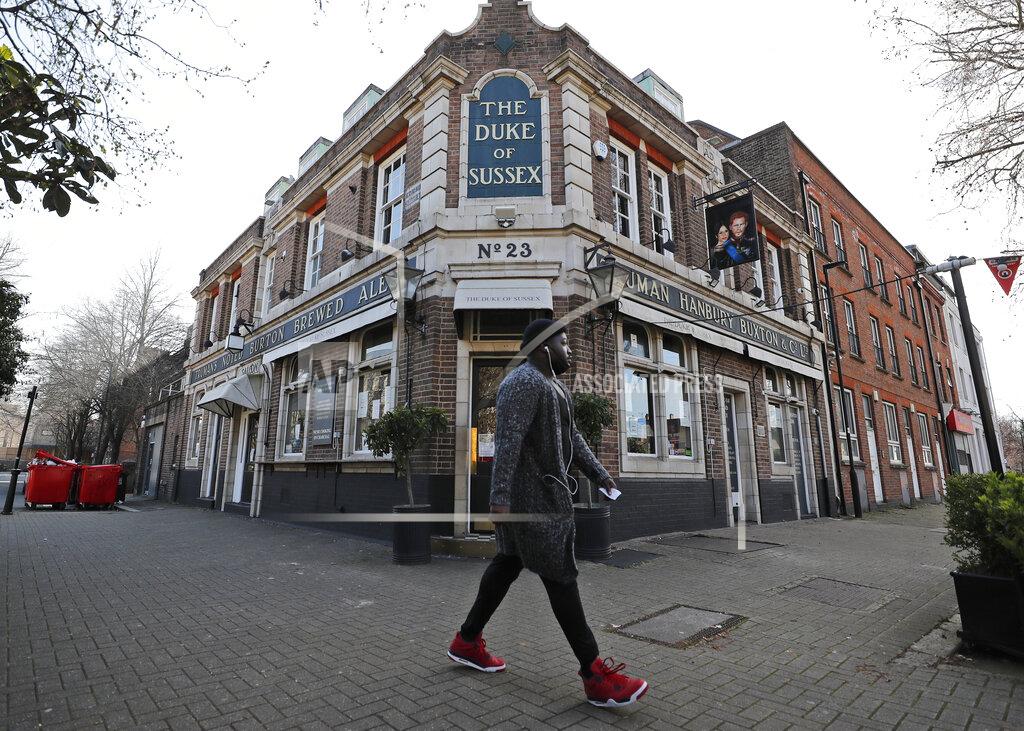 Frank Augstein A man walks past the Duke of Sussex pub with a sign depicting the image of Britain's Prince Harry and his wife Meghan, near Waterloo station, London, Tuesday March 9, 2021. Prince Harry and Meghan's explosive TV interview has divided people around the world, rocking an institution that is struggling to modernize with claims of racism and callousness toward a woman struggling with suicidal thoughts. (AP Photo/Frank Augstein)