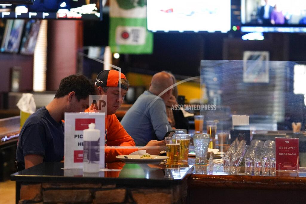 Darron Cummings Fans gather at the bar while being socially distant at Kilroy's Bar & Grill, Sunday, March 14, 2021, in Indianapolis. The NCAA Tournament and bars were made for each other, with fans of powerhouse teams like Gonzaga and longshots like Colgate pouring in to cheer their teams. Until last year, that is, when COVID-19 blew up everybody’s brackets. This year, the tournament’s back, and bars and restaurants, some shuttered for months, are open for March Madness, though things may look a little different.(AP Photo/Darron Cummings)