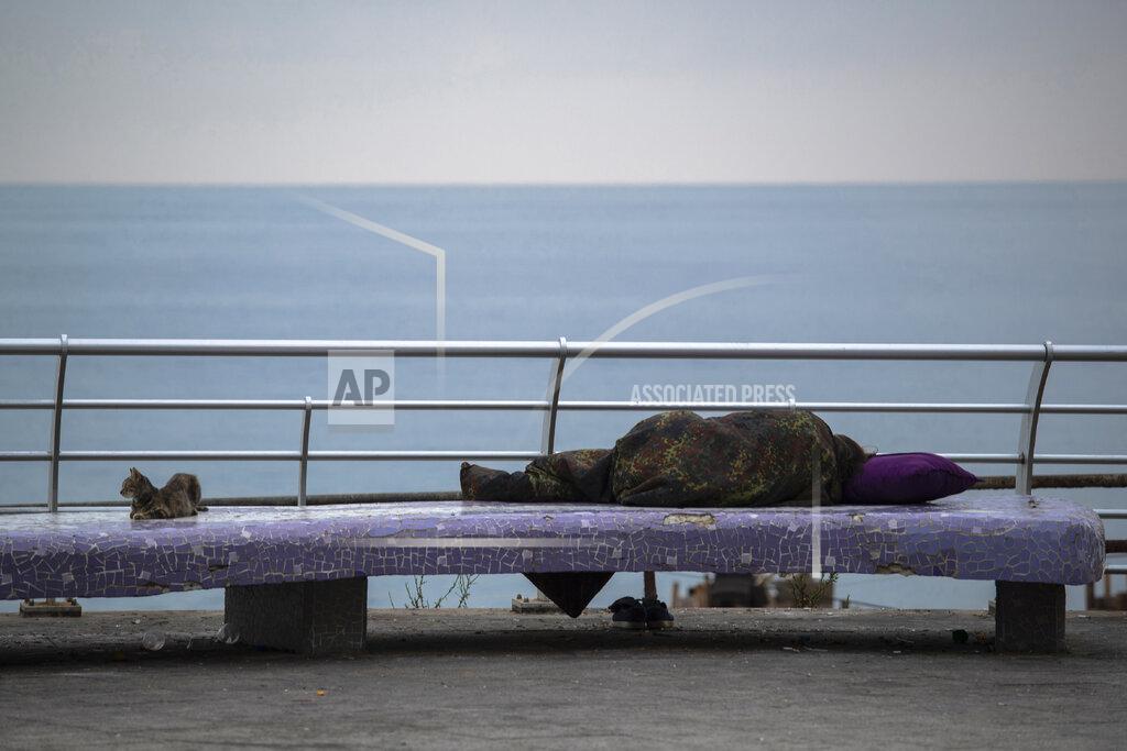 FILE - In this, July 19, 2020 file photo, a homeless woman sleeps on a bench on the Mediterranean Sea corniche in Beirut, Lebanon. The World Bank has approved a $246 million loan to Lebanon to provide emergency cash assistance to nearly 800,000 Lebanese reeling under the country’s compounded economic and health crises. The World Bank said in a statement late Tuesday, Jan. 12, 2021, that the loan would also support the development of a national social safety net in Lebanon. (AP Photo/Hassan Ammar, File)