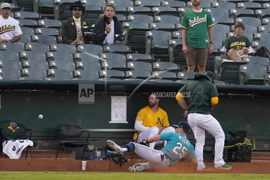 Jeff Chiu Seattle Mariners left fielder Dylan Moore (25) cannot catch a foul ball hit by Oakland Athletics' Matt Olson as he slides into the Athletics bullpen during the first inning of a baseball game in Oakland, Calif., Monday, Sept. 20, 2021. (AP Photo/Jeff Chiu)