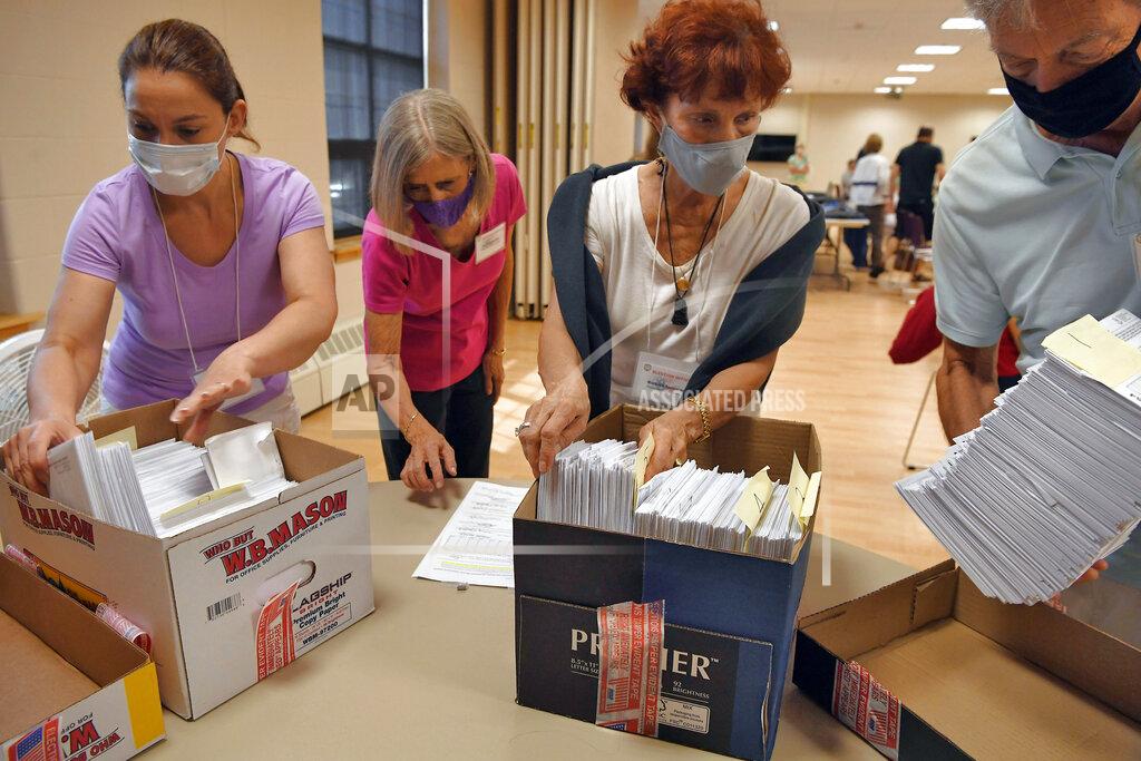 FILE - In this Aug. 11, 2020, file photo, volunteers sort mail-in ballots on Primary Day, in Glastonbury, Conn. Town and city clerks across Connecticut have been enlisting volunteers, hiring extra staff and paying overtime to workers to process an unprecedented number of requests for absentee election ballots. (AP Photo/Jessica Hill, File)