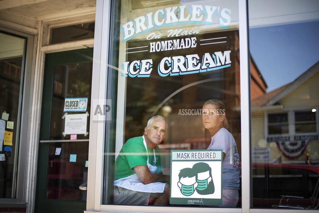 David Goldman Steve, left, and Chris Brophy, husband and wife owners of Brickley's Ice Cream, look out from the shop they closed after teenage workers were harassed by customers who refused to wear a mask or socially distance, in Wakefield, R.I., Wednesday, July 29, 2020. "Some of them don't believe it's real (COVID-19) and some don't think it's a big deal, I do," Steve Brophy said, adding that he would rather close than put young workers and customers at risk of harassment, and the virus. "It's like it's OK to be a jerk in this environment." (AP Photo/David Goldman)