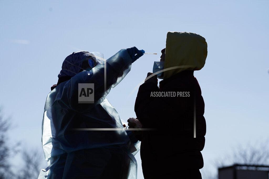 Registered nurse Tria Jones, left, swabs a patient during testing for COVID-19 organized by Philadelphia FIGHT Community Health Centers at Mifflin Square Park, Thursday, Dec. 10, 2020, in south Philadelphia. (AP Photo/Matt Slocum)