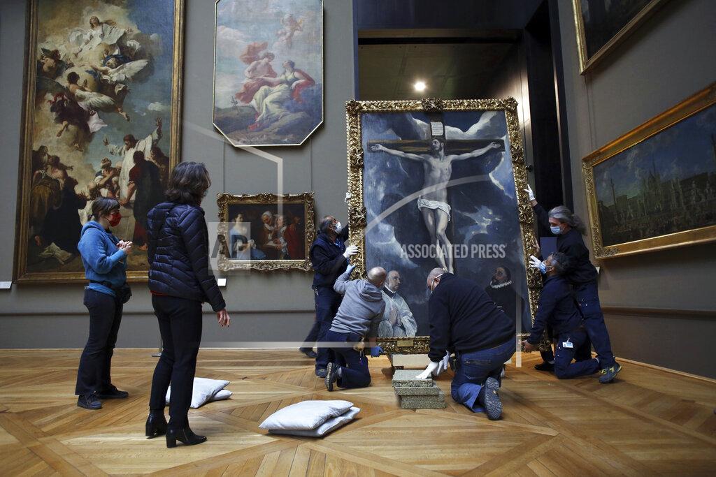 Thibault Camus Workers handle a painting called 'Christ on the Cross Adored by Two Donors' by Spanish painter El Greco, as it returns from an exhibition at the Chicago Institute, in the Louvre museum, in Paris, Tuesday, Feb. 9, 2021. The forced closure has also granted museum officials a golden opportunity to carry out long-overdue refurbishments that were simply not possible with nearly 10 million visitors a year. (AP Photo/Thibault Camus)