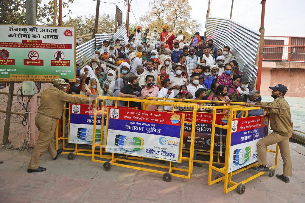 Karma Sonam Devotees stand behind barricades as they wait for Naga Sadhu or Naked Hindu holy men to arrive for Shahi snan or a Royal bath during Kumbh mela, in Haridwar in the Indian state of Uttarakhand, Monday, April 12, 2021. As states across India are declaring some version of a lockdown to battle rising Covid cases as part of a nationwide second-wave, thousands of pilgrims are gathering on the banks of the river Ganga for the Hindu festival Kumbh Mela. The faithful believe that a dip in the waters of the Ganga will absolve them of their sins and deliver them from the cycle of birth and death. (AP Photo/Karma Sonam)