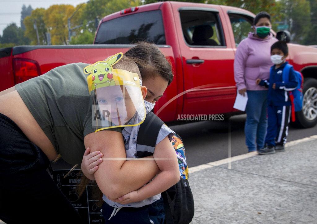 FILE - In this Sept. 21, 2020, file photo, Vanessa Mendez hugs her son, Evan Seppa, as he prepares to head into Elizabeth Page Elementary School for his first day of kindergarten in Springfield, Ore. Even as the federal Centers for Disease Control and Prevention moved earlier this month to ease indoor mask-wearing guidance for fully vaccinated people, states like Oregon and Washington are still holding on to certain longtime coronavirus restrictions. (Andy Nelson/The Register-Guard via AP, File)