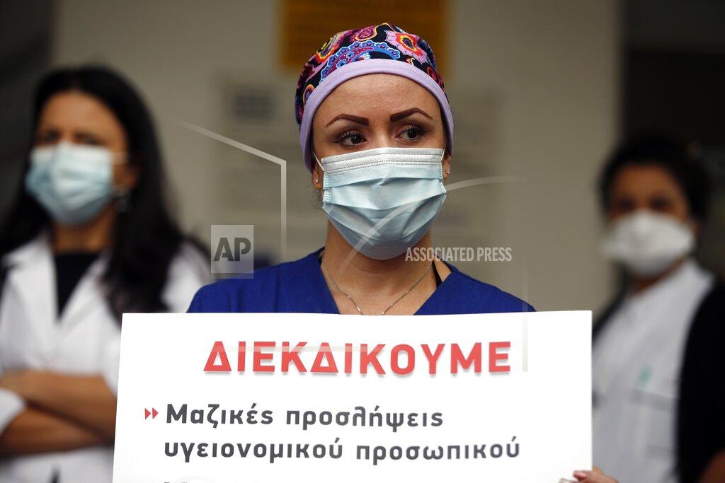 Thanassis Stavrakis Intensive Care Unit (ICU) nurse Anna Kaloudi wearing a face mask to protect against the spread of the coronavirus, holds a placard that reads "We seek mass hirings of health workers" during a protest at Evangelismos hospital in Athens, Thursday, Nov. 12, 2020. State health workers' union staged protests at several hospitals around the country to demand more hiring. Greece has imposed a nationwide nightly curfew as the number of COVID-19 cases in the country continues to surge despite a lockdown. (AP Photo/Thanassis Stavrakis)