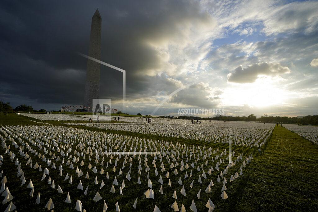 Brynn Anderson With the Washington Monument in the background, people look at white flags that are part of artist Suzanne Brennan Firstenberg's temporary art installation, "In America: Remember," in remembrance of Americans who have died of COVID-19, on the National Mall in Washington, Friday, Sept. 17, 2021. The installation consists of more than 630,000 flags. (AP Photo/Brynn Anderson)