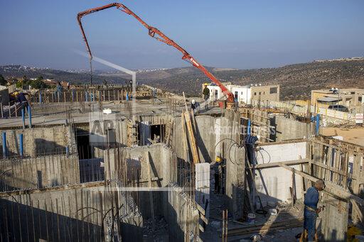 FILE - In this Monday, Oct. 25, 2021 file photo, Palestinian laborers work building new houses in the West Bank Jewish settlement of Bruchin near the Palestinian town of Nablus, Monday, Oct. 25, 2021. An Israeli settlement monitor said Wednesday that Israel has approved about 3,000 settler homes in the occupied West Bank. The decision by a government committee came a day after the Biden administration issued its strongest condemnation yet of the proposed construction. (AP Photo/Ariel Schalit, File)