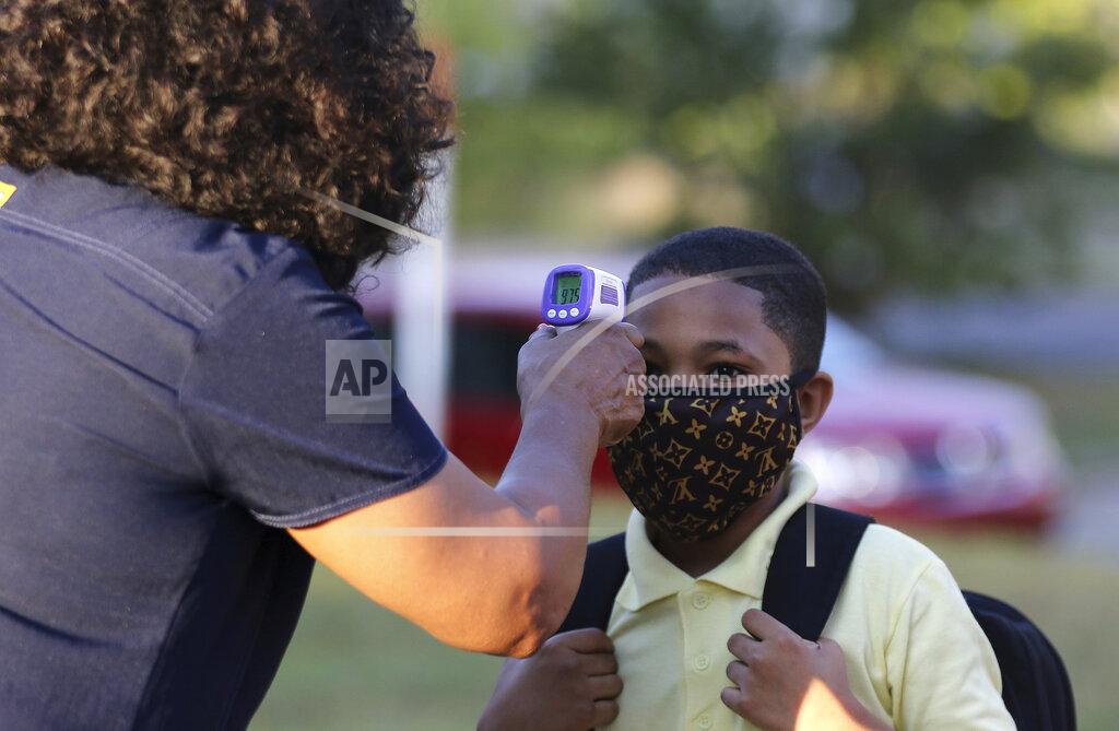 Tommy Metthe Fifth-grader Marcques Haley, 10, gets his temperature checked by the school nurse, Rachel White, before entering the building on Monday, Aug. 24, 2020, at Stephens Elementary School in Little Rock, Arkansas. (Tommy Metthe /The Arkansas Democrat-Gazette via AP)