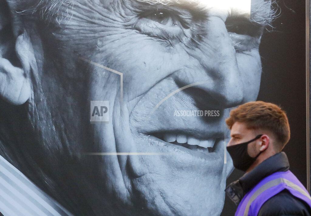Frank Augstein A man walks past a portrait of Britain's Prince Philip ahead of his funeral in Windsor, England Saturday April 17, 2021. Philip died April 9 at the age of 99 after 73 years of marriage to Britain's Queen Elizabeth II. Coronavirus restrictions mean there will be only 30 mourners for the service, including the widowed queen, her four children and her eight grandchildren. (AP Photo/Frank Augstein)