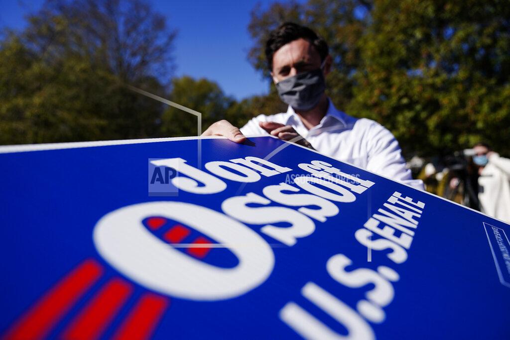 Brynn Anderson FILE-In this Wednesday, Nov. 18, 2020 file photo, Georgia Democratic candidate for U.S. Senate Jon Ossoff grabs signs to give out during a drive-thru yard sign pick-up event on, in Marietta, Ga. For the second time in three years, Jon Ossoff is campaigning in overtime. The question is whether the 33-year-old Democrat can deliver a win in a crucial Jan. 5 runoff with Republican Sen. David Perdue. (AP Photo/Brynn Anderson, File)