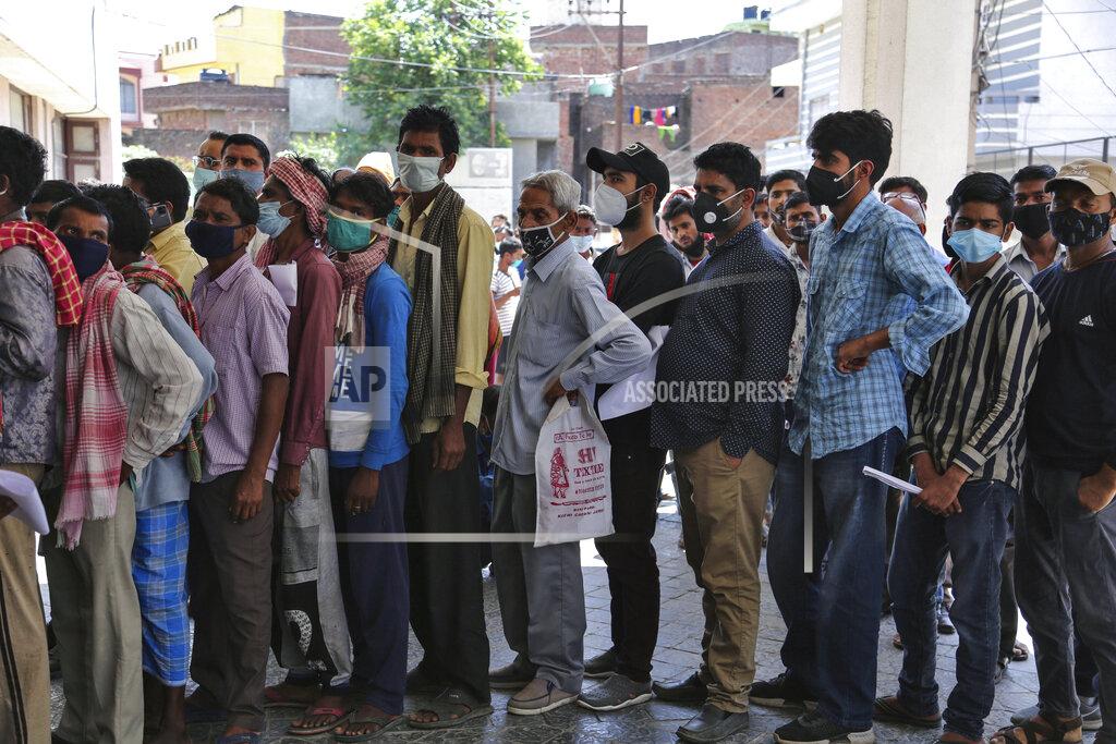 Channi Anand FILE- In this April 19, 2021 file photo, people wearing face masks as a precaution against the coronavirus line up without any physical distancing to get tested for COVID-19 at a government hospital in Jammu, India. India's health system is collapsing under the worst surge in coronavirus infections that it has seen so far. Medical oxygen is scarce. Intensive care units are full. Nearly all ventilators are in use, and the dead are piling up at crematoriums and graveyards. Such tragedies are familiar from surges in other parts of the world — but were largely unknown in India. (AP Photo/Channi Anand, File)