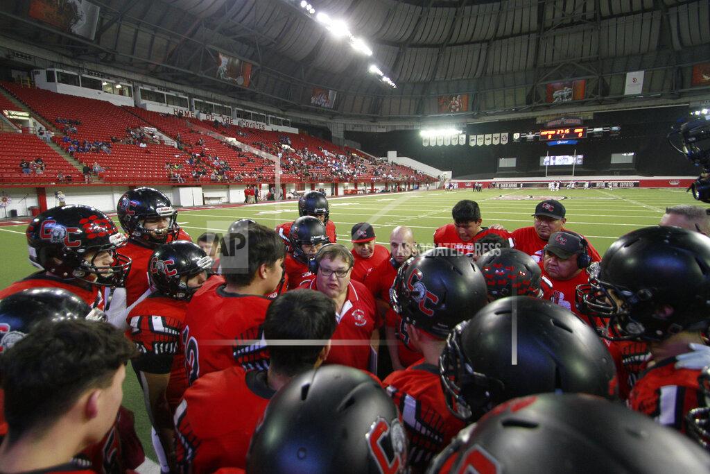 Stephen Groves In this Nov. 8, 2019 photo, Crow Creek Chieftains coach Scott Klaudt, center, instructs his team before the All Nations Football Conference championship game in Vermillion, South Dakota. (AP Photo/Stephen Groves)