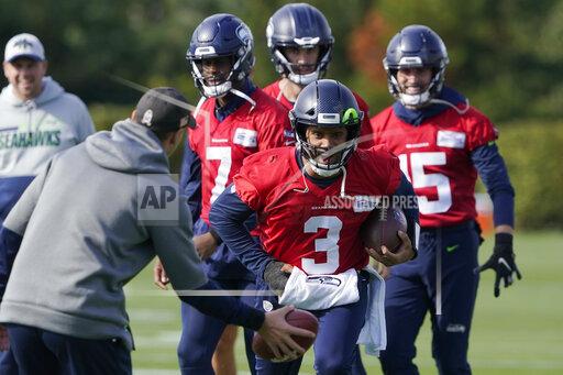 Seattle Seahawks quarterback Russell Wilson (3) keeps his injured hand in a pad as he runs through a warmup drill with backup quarterback Geno Smith (7) behind him during NFL football practice, Wednesday, Oct. 13, 2021, in Renton, Wash. Wilson had surgery on his hand last Friday, and Smith is expected to be the starting quarterback Sunday when the Seahawks play the Pittsburgh Steelers on the road. (AP Photo/Ted S. Warren)