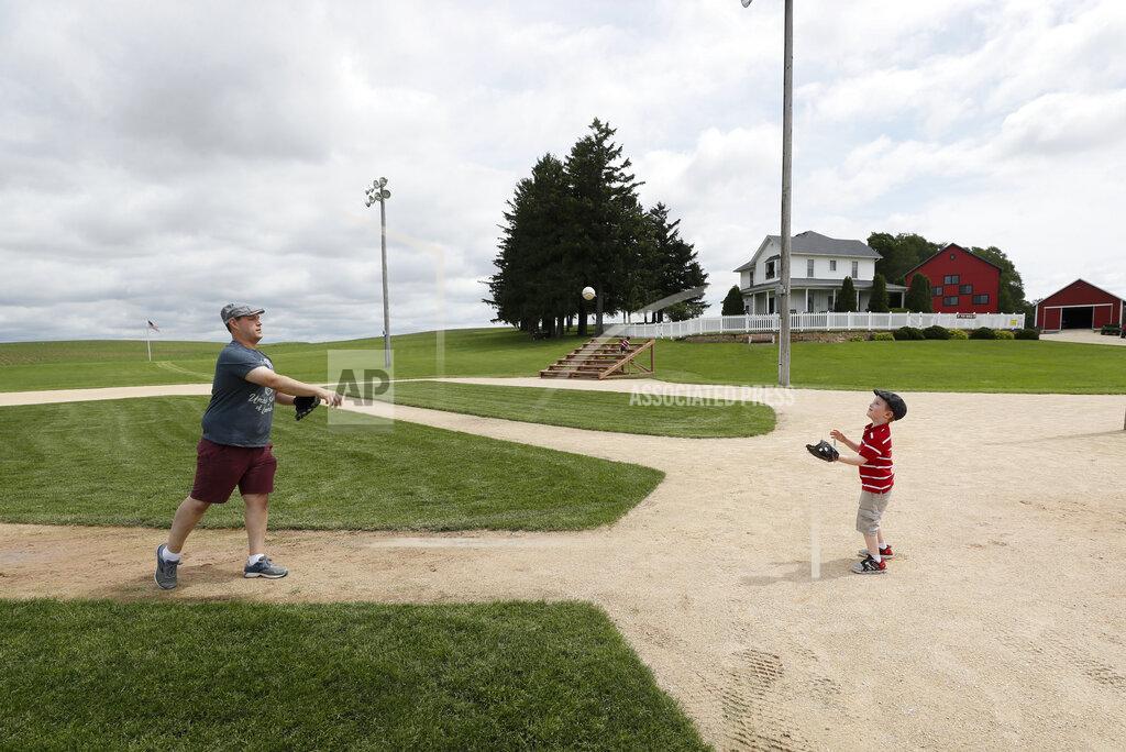 Charlie Neibergall Jeremiah Bronson, of Ames, Iowa, plays catch with his sone Ben, right, on the field at the Field of Dreams movie site, Friday, June 5, 2020, in Dyersville, Iowa. Major League Baseball is building another field a few hundred yards down a corn-lined path from the famous movie site in eastern Iowa but unlike the original, it's unclear whether teams will show up for a game this time as the league and its players struggle to agree on plans for a coronavirus-shortened season. (AP Photo/Charlie Neibergall)