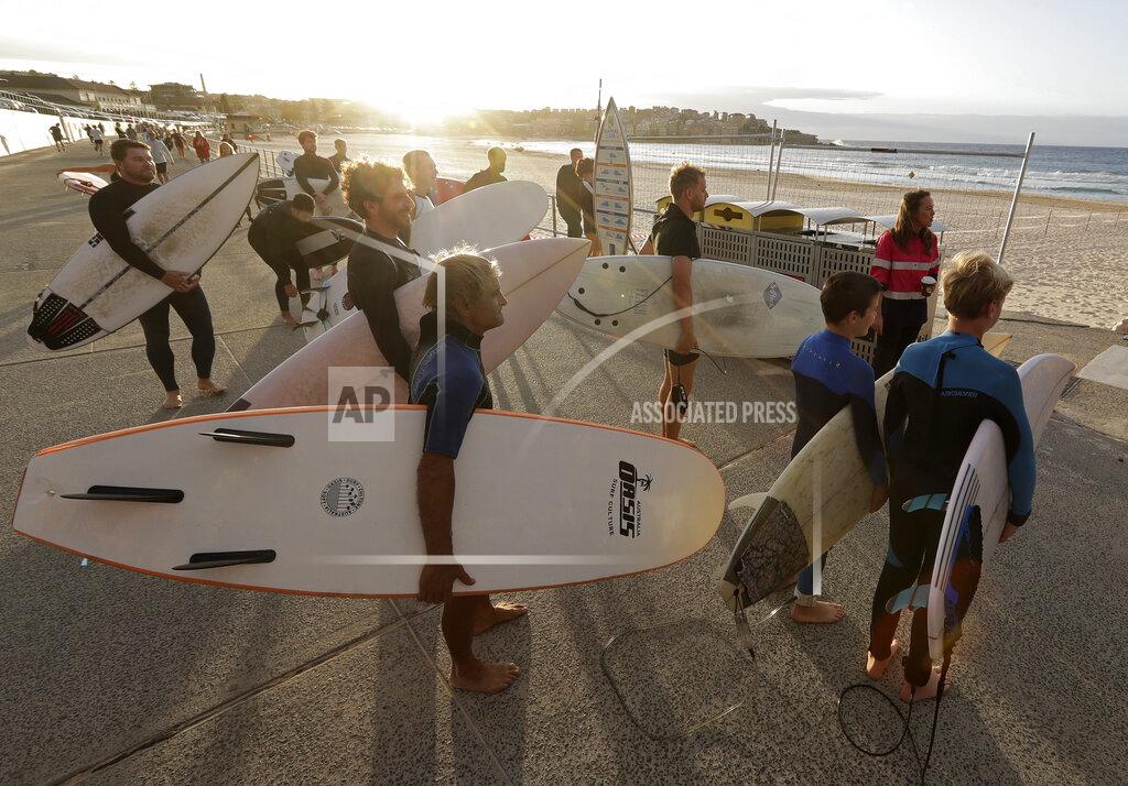 Rick Rycroft Surfers wait for officials to open Bondi Beach in Sydney, Tuesday, April 28, 2020, as coronavirus pandemic restrictions are eased. The beach is open to swimmers and surfers to exercise only. (AP Photo/Rick Rycroft)
