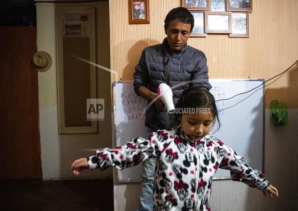 Esteban Felix Jose Collantes blow-dries his daughter Kehity's hair as he gets her ready for bed at their home where they live with Jose's sister in Santiago, Chile, Monday, Aug. 17, 2020, two months after the death of his wife, her mother, to COVID-19. When Collantes' wife, Silvia Cano, was still alive in the hospital, it was the first time he was completely in charge of his daughter and running their home, and by phone, his wife even told him how to bake bread for Kehity. (AP Photo/Esteban Felix)
