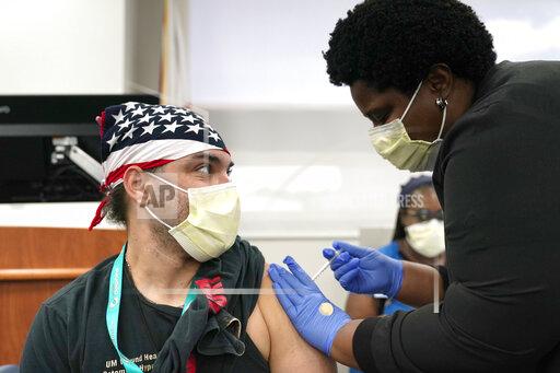 Hector Montoto, left, receives a Pfizer COVID-19 booster shot from registered nurse Ekaete Ikpeinyang, right, at Jackson Memorial Hospital Tuesday, Oct. 5, 2021, in Miami. This follows a recent recommendation by the Food and Drug Administration and Centers for Disease Control and Prevention advising people who are 65 and older, and workers whose jobs put them at high risk of exposure – including those in healthcare – to receive a booster shot six months after their second shot. (AP Photo/Lynne Sladky)
