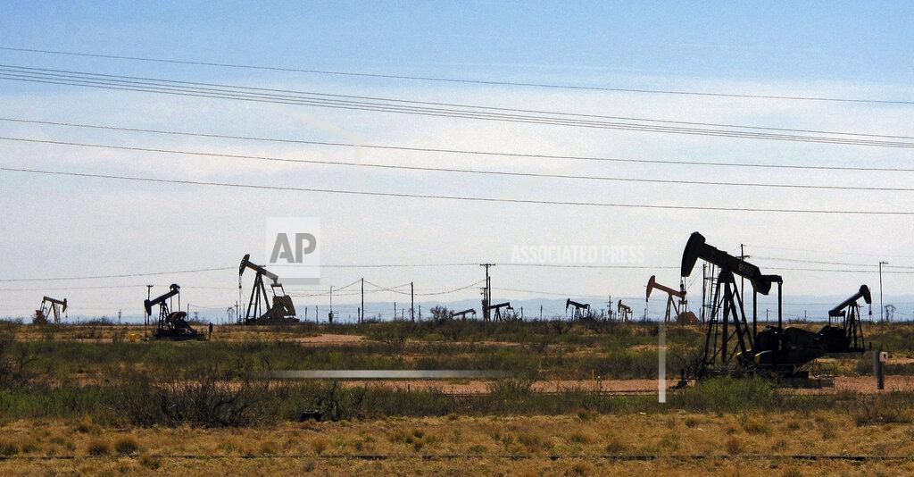 Jeri Clausing FILE - Oil rigs stand in the Loco Hills field along U.S. Highway 82 in Eddy County, near Artesia, N.M., one of the most active regions of the Permian Basin. Government budgets are booming in New Mexico. The reason behind the spending spree — oil. New Mexico is the No. 2 crude oil producer among U.S. states and the top recipient of U.S. disbursements for fossil fuel production on federal land. But a budget flush with petroleum cash has a side effect: It also puts the spotlight on how difficult it is for New Mexico and other states to turn their rhetoric on tackling climate change into reality. (AP Photo/Jeri Clausing, File)