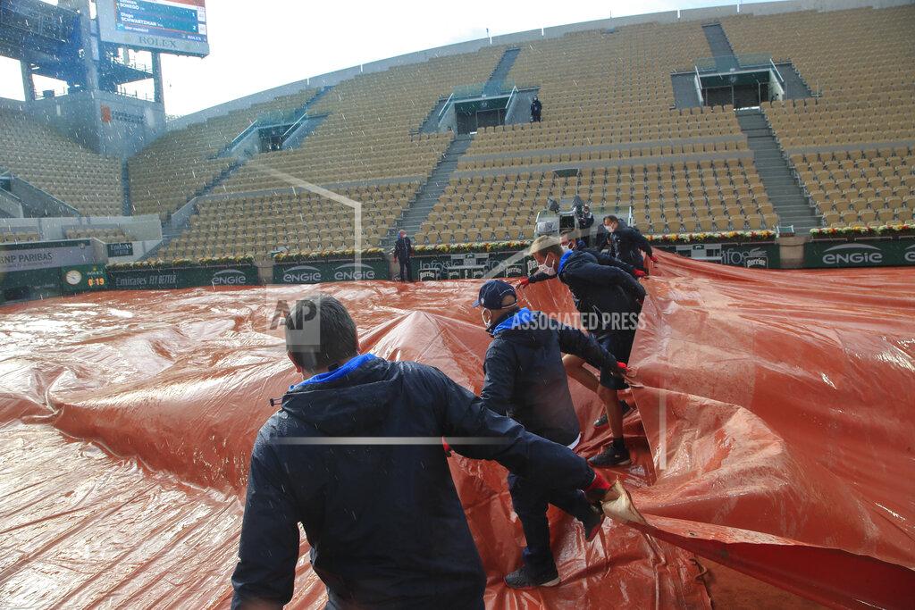 Michel Euler Stadium workers cover Suzanne Lenglen court as rain suspended play in the fourth round match of the French Open tennis tournament between Argentina's Diego Schwartzman and Italy's Lorenzo Sonego at the Roland Garros stadium in Paris, France, Sunday, Oct. 4, 2020. (AP Photo/Michel Euler)