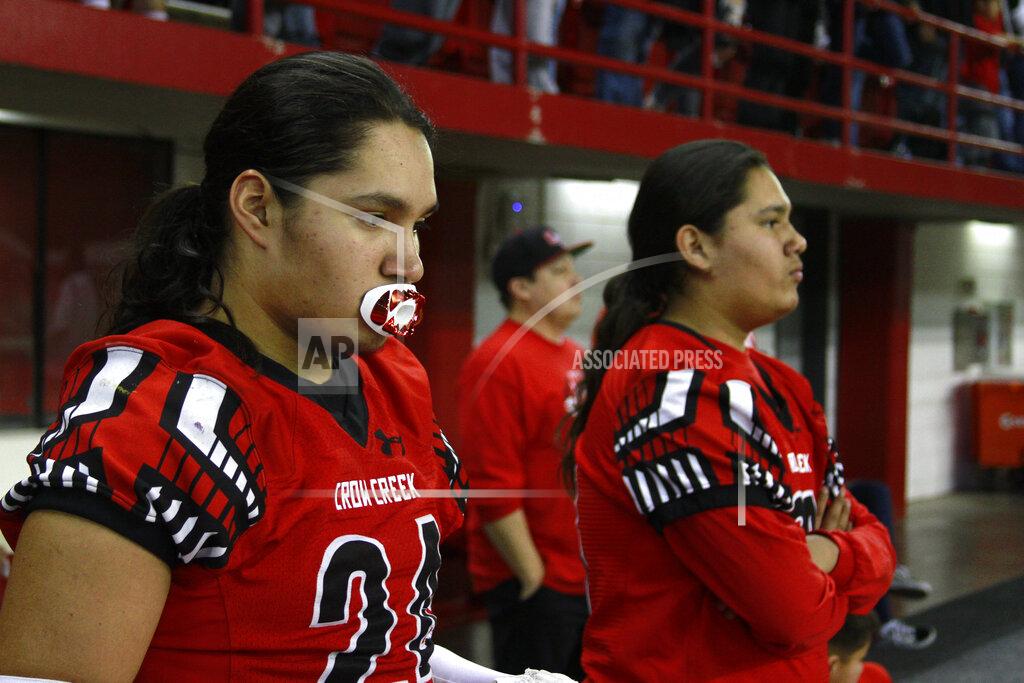 Stephen Groves In this Nov. 8, 2019 photo, Jayton Pease, left, waits to get on the field alongside his brother Jashawn, before the All Nations Football Conference championship in Vermillion, S.D. Jashawn and Jayton Pease shed tears as the Crow Creek Chieftains won the first All Nations Conference championship, and then remembered their older brother one of too many American Indians to die by suicide on a reservation with the highest suicide rate in South Dakota. (AP Photo/Stephen Groves)