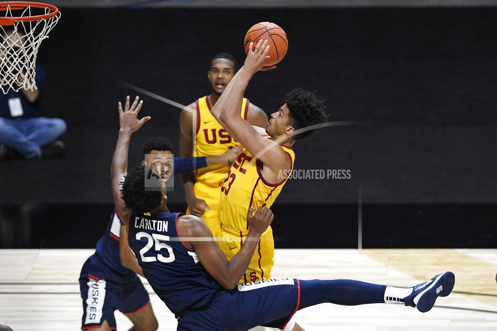 Jessica Hill Connecticut's Josh Carlton (25) fouls Southern California's Max Agbonkpolo during the first half of an NCAA college basketball game Thursday, Dec. 3, 2020, in Uncasville, Conn. (AP Photo/Jessica Hill)