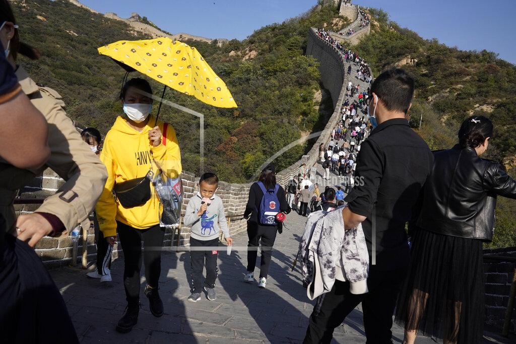 Ng Han Guan A child lowers his mask to enjoy an ice cream as he climbs up a stretch of the Badaling Great Wall of China on the outskirts of Beijing on Tuesday, Oct. 6, 2020. Chinese tourists took 425 million domestic trips in the first half of the eight-day National Day holiday, generating $45.9 billion in tourism revenue, according to China's ministry of culture and tourism. The holiday this year, which coincides with the Mid-Autumn Festival, will be a litmus test of whether China's tourism industry can bounce back after being battered by COVID-19. (AP Photo/Ng Han Guan)