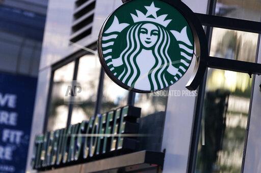 The "Siren" logo hangs outside a Starbucks Coffee shop, Wednesday, July 14, 2021, in Boston. Starbucks said Wednesday, Oct. 27 it is raising its U.S. employees’ pay and making other changes to improve working conditions in its stores. (AP Photo/Charles Krupa)