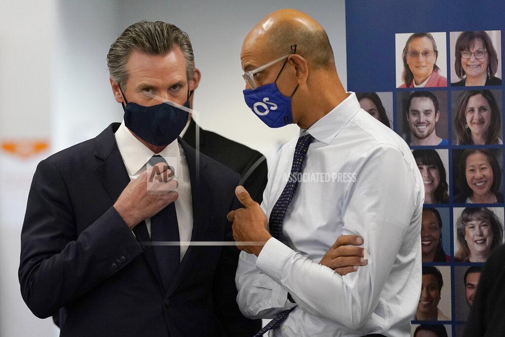 Jeff Chiu Gov. Gavin Newsom, left, speaks with Dr. Mark Ghaly, Secretary of the California Health and Human Services, at a news conference in Oakland, Calif., Monday, July 26, 2021. California will require state employees and all health care workers to show proof of COVID-19 vaccination or get tested weekly. Officials are tightening restrictions in an effort to slow rising coronavirus infections in the nation's most populous state, mostly among the unvaccinated. (AP Photo/Jeff Chiu)