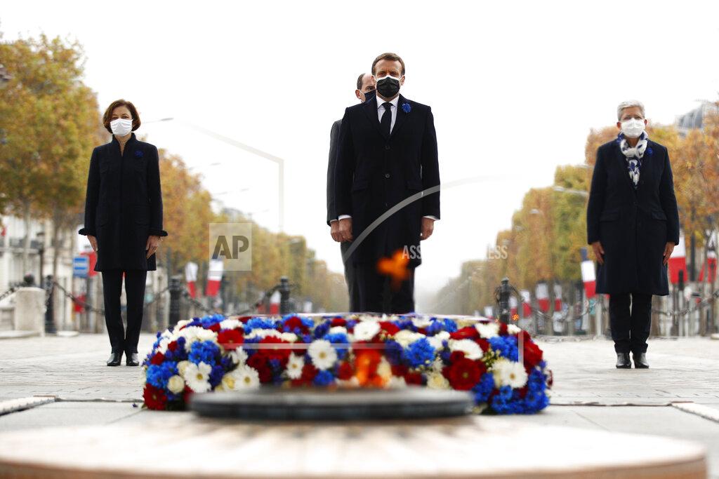 Yoan Valat French President Emmanuel Macron, center foreground, French Prime Minister Jean Castex, center background, and French Defence Minister Florence Parly, left, stand at the tomb of the unknown soldier under the Arc de Triomphe during Armistice Day ceremonies marking the end of World War I, in Paris, Wednesday, Nov. 11, 2020. French President Emmanuel Macron is commemorating the 102nd anniversary of the armistice ending World War I and honoring all those who have died for France in two elaborate, solemn ceremonies Wednesday. (Yoan Valat/Pool via AP)