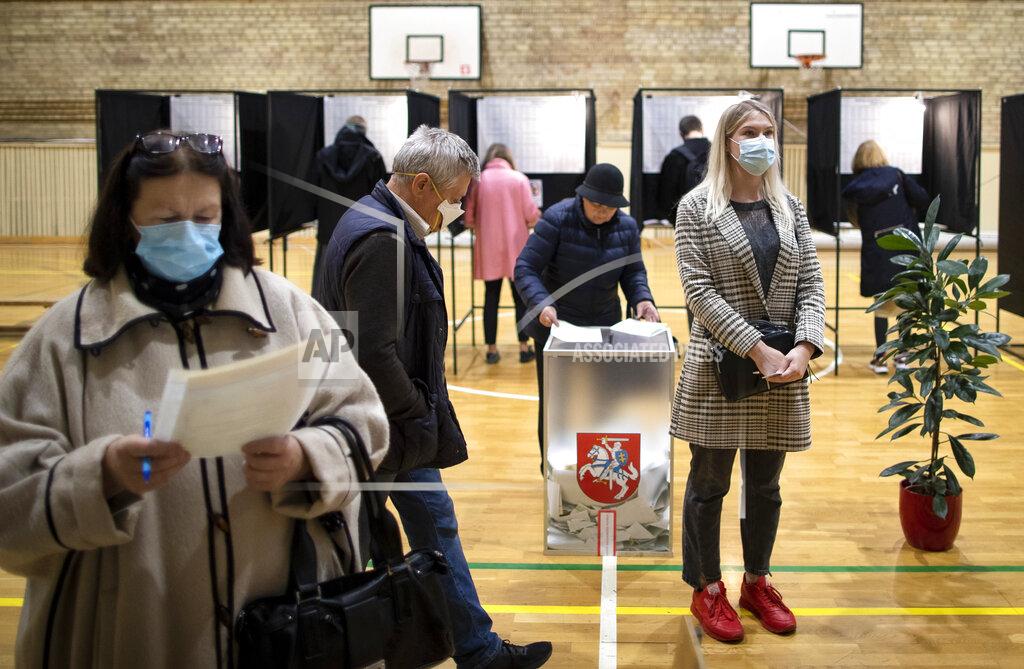 Mindaugas Kulbis People wear face masks to protect against coronavirus as they cast their ballots during the parliamentary elections in Vilnius, Lithuania, Sunday, Oct. 11, 2020. Polls opened Sunday for the first round of national election in Lithuania, where voters will renew the 141-seat parliament and the ruling four-party coalition is widely expected to face a stiff challenge from the opposition to remain in office. (AP Photo/Mindaugas Kulbis)