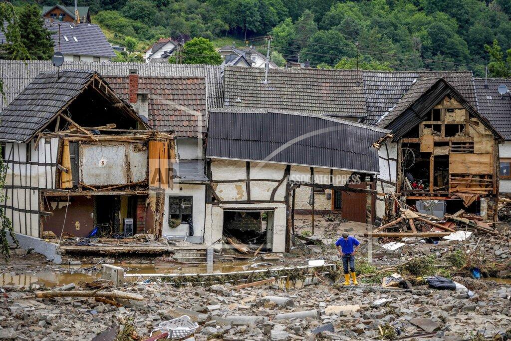 Michael Probst FOR HOLD -FILE - In this Thursday, July 15, 2021, file photo, a person stands in front of destroyed houses in Schuld, Germany, after massive floods in the region. Germany's parliament last week approved a 30 billion-Euro, 35 billion Dollars, rebuilding fund for the swath of western Germany affected by the flooding. Overseeing that long-term effort will fall to Germany's next administration. (AP Photo/Michael Probst, File)