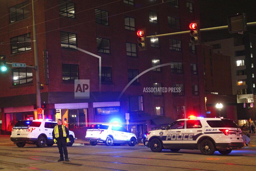 Ted S. Warren Tacoma Police and other law enforcement vehicles are shown near the site of a car crash Saturday, Jan. 23, 2021, in downtown Tacoma, Wash. At least one person was injured when a police car plowed through a crowd of people Saturday night who were watching a downtown street race, the Tacoma News-Tribune reported. (AP Photo/Ted S. Warren)