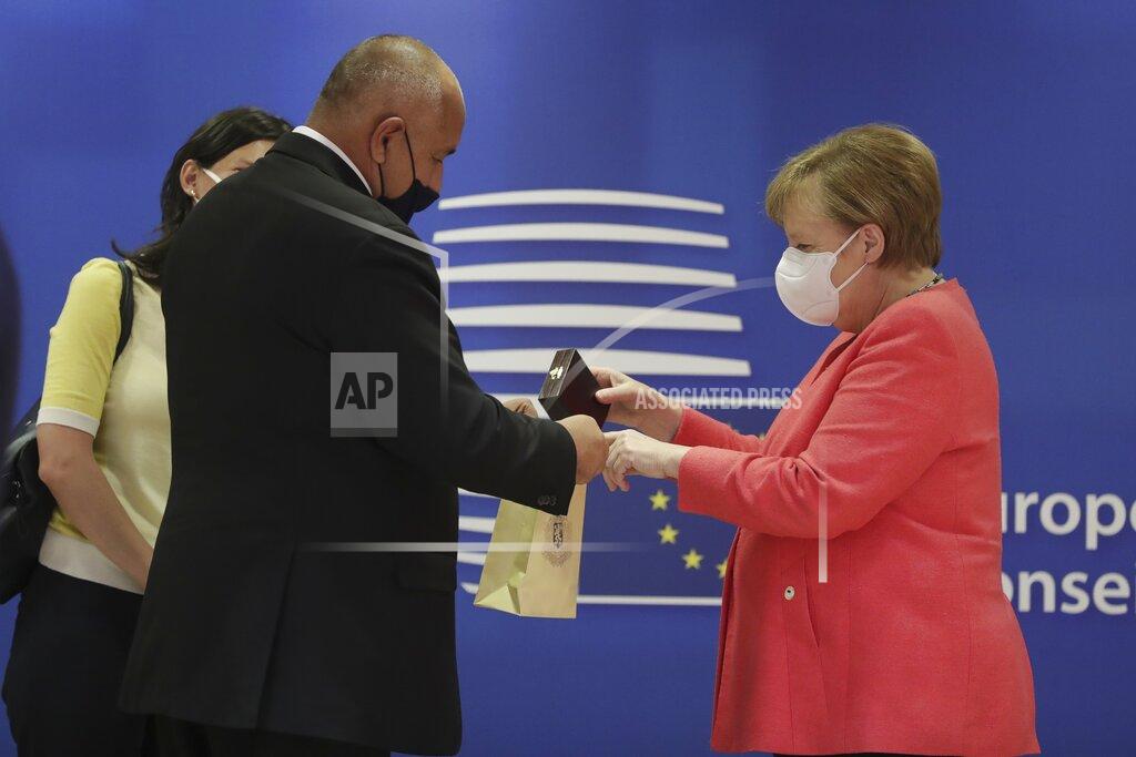 Stephanie Lecocq German Chancellor Angela Merkel, right, puts a gift in a bag as she speaks with Bulgaria's Prime Minister Boyko Borissov during a round table meeting at an EU summit in Brussels, Friday, July 17, 2020. Leaders from 27 European Union nations meet face-to-face on Friday for the first time since February, despite the dangers of the coronavirus pandemic, to assess an overall budget and recovery package spread over seven years estimated at some 1.75 trillion to 1.85 trillion euros. (Stephanie Lecocq, Pool Photo via AP)