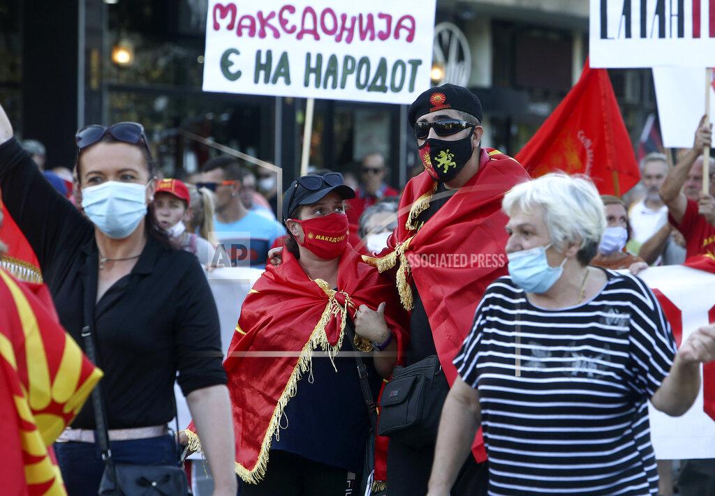 Boris Grdanoski People wearing face masks protest the change of the country's name to North Macedonia and "disparage" of the Macedonian national identity and dignity in a process of country's Euro-Atlantic integration, in front of the parliament building in Skopje, North Macedonia, Sunday, Aug. 30, 2020. North Macedonia’s parliament continued its debate on a vote of confidence for a new left-wing coalition government after the Social Democrats and their ethnic Albanian partners secured a majority in parliament in July's general election. (AP Photo/Boris Grdanoski)