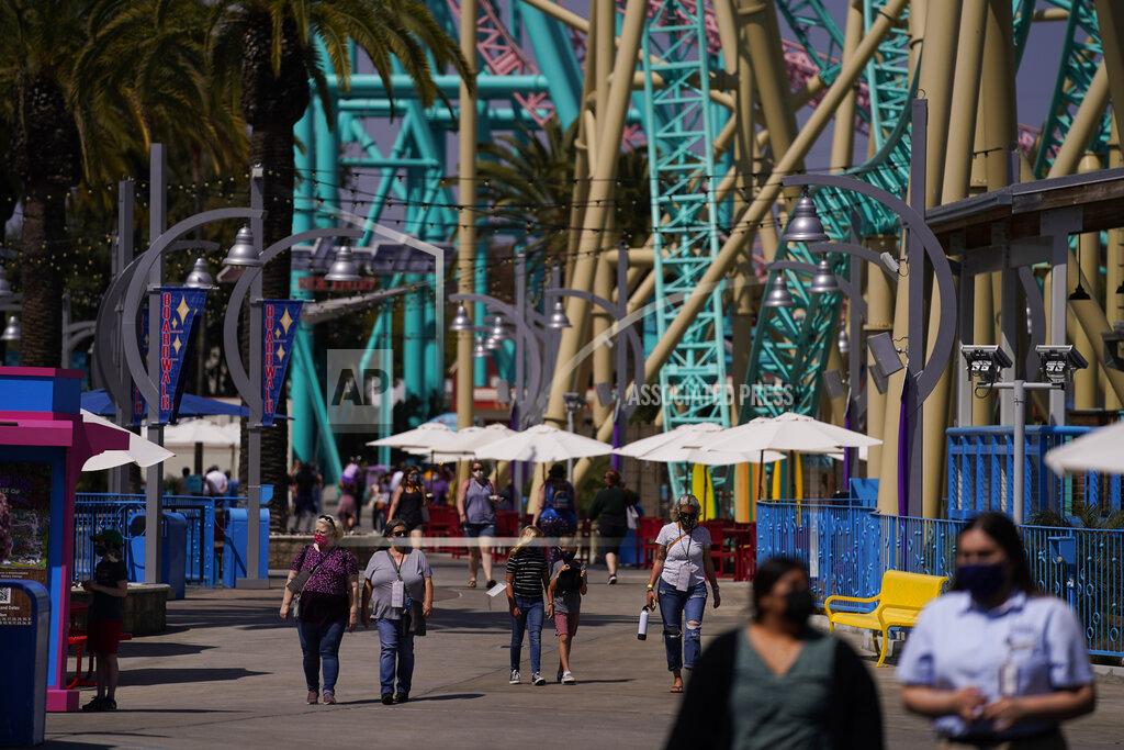 Jae C. Hong Visitors walk past rides during the Knott's Taste of Boysenberry Festival at Knott's Berry Farm in Buena Park, Calif., Tuesday, March 30, 2021. Massive Los Angeles County can reopen even more businesses, California public health officials announced Tuesday. The county of 10 million people was one of several counties, including neighboring Orange County, that moved into the state's second-least restrictive orange tier amid low coronavirus case rates. (AP Photo/Jae C. Hong)