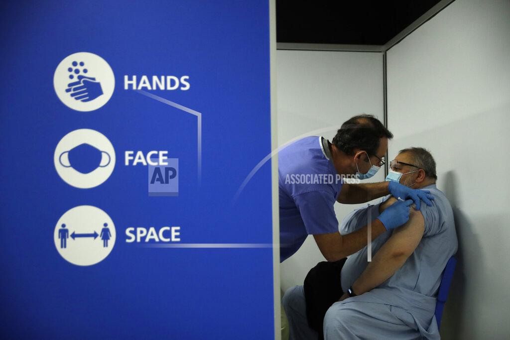 Matt Dunham FILE - In this May 1, 2021, file photo, Maoula Jan, 52, receives his second dose of the Pfizer vaccine for coronavirus from volunteer Steve Kriss, at a vaccine center in the Swaminarayan School in Neasden, north London. Britain's Conservative government is hoping a combination of relatively high vaccination rates and common-sense behavior will keep a lid on coronavirus infections this fall and winter and avoid the need for restrictive measures. (AP Photo/Matt Dunham, File)