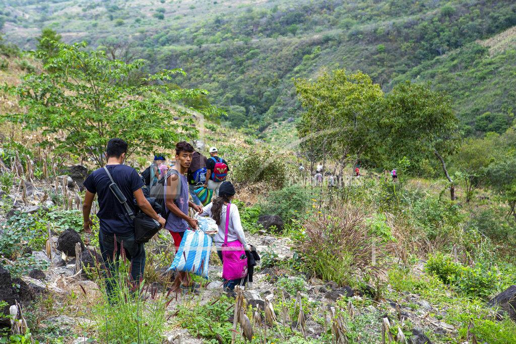 Oliver De Ros Honduran migrants trying to reach the U.S. take a path through the mountains to avoid the highway police checkpoints, in Chiquimula, Guatemala, Tuesday, Jan. 19, 2021. A once large caravan of Honduran migrants that pushed its way into Guatemala last week had dissipated by Tuesday in the face of Guatemalan security forces. (AP Photo/Oliver de Ros)