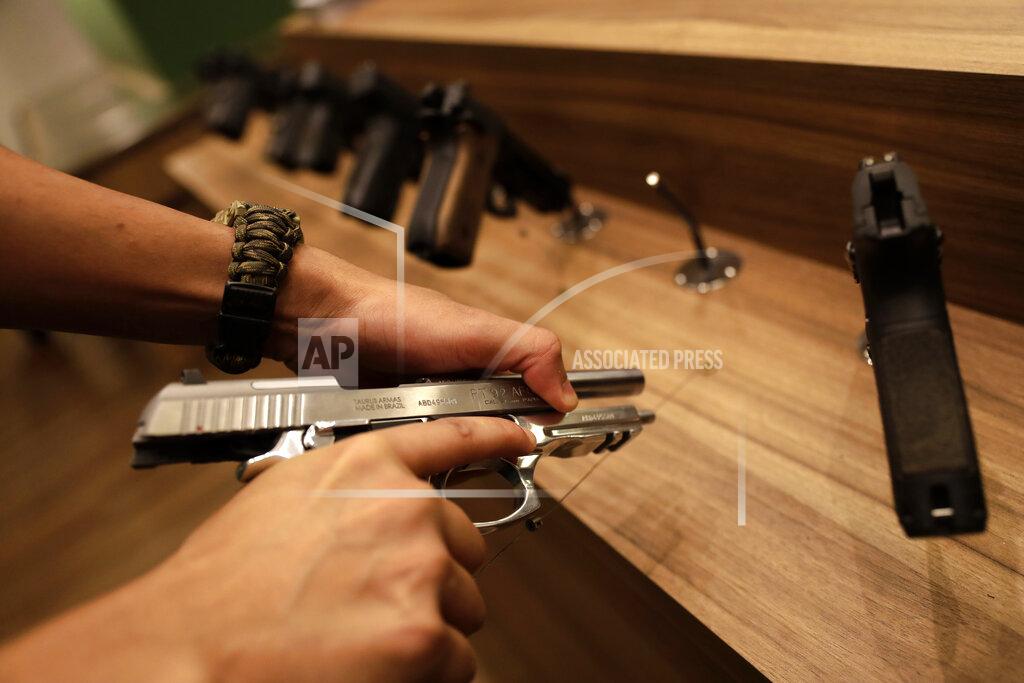 Eraldo Peres A seller demonstrates a gun inside the Big Boar gun shop in Brasilia, Brazil, Thursday, March 4, 2021. President Jair Bolsonaro signed four decrees that, among other things, will allow Brazilians to buy up to 8 guns, and carry two guns simultaneously – unless lawmakers vote down the measures. (AP Photo/Eraldo Peres)