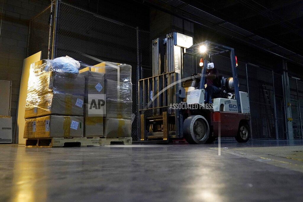 Ross D. Franklin A worker picks up one of the dozens of pallets of more with one million pieces of PPE to help Phoenix schools reopen for the 2020-2021 school year fill a Phoenix Convention Center hall as the City of Phoenix begins to ship the pallets out to schools Tuesday, Sept. 8, 2020, in Phoenix. (AP Photo/Ross D. Franklin)