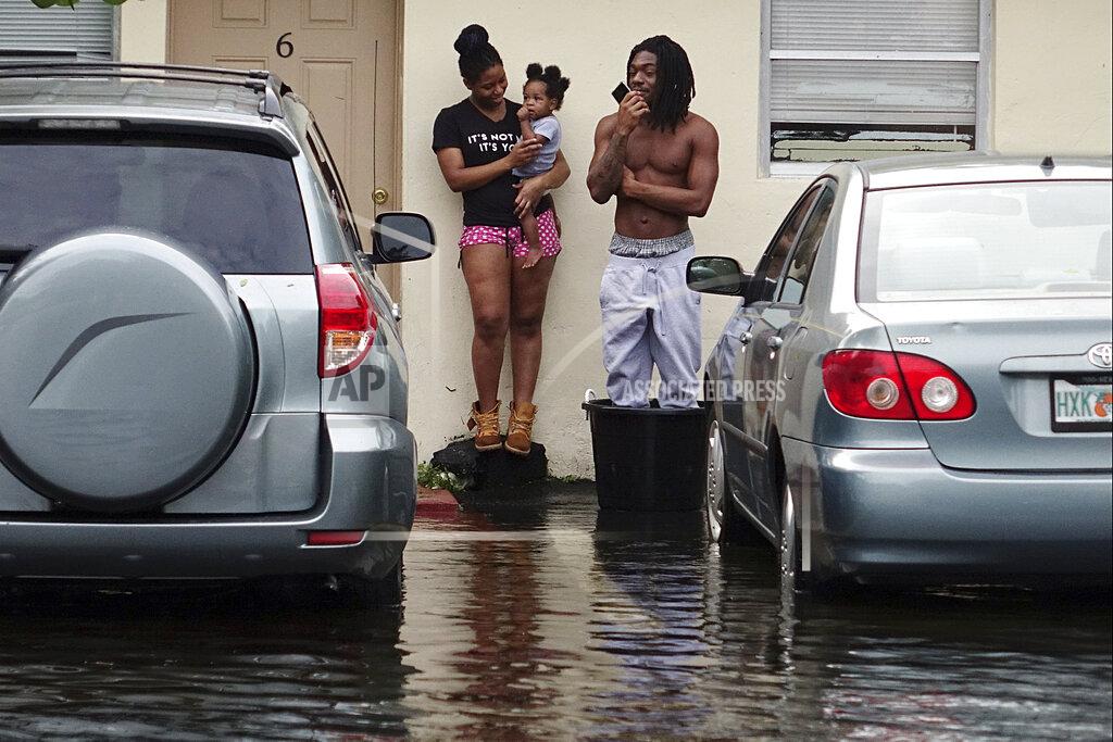 Joe Cavaretta Evan and Denise Knight try to keep dry along with their baby Zion, on a flooded street in Melrose Park in Fort Lauderdale, Fla., Monday, Nov. 9, 2020. Heavy rain from Tropical Storm Eta caused dangerous flooding Monday across Florida's most densely populated urban areas, stranding cars and swamping entire neighborhoods with fast-rising water that had no place to drain. (Joe Cavaretta/South Florida Sun-Sentinel via AP)