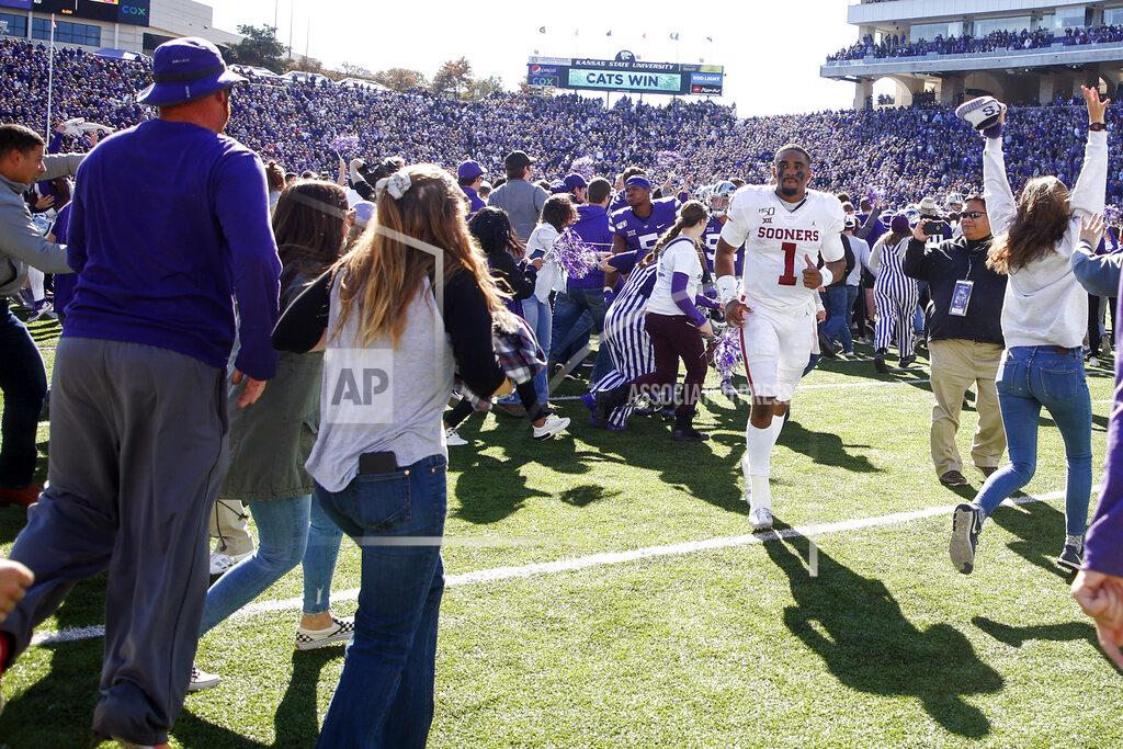 Ian Maule Kansas State fans storm the field as Oklahoma quarterback Jalen Hurts (1) attempts to head towards the locker room after the Sooners loss to the Wildcats in an NCAA football game at Bill Snyder Family Stadium in Manhattan, Kan., Saturday, Oct. 26, 2019. (Ian Maule/Tulsa World via AP)