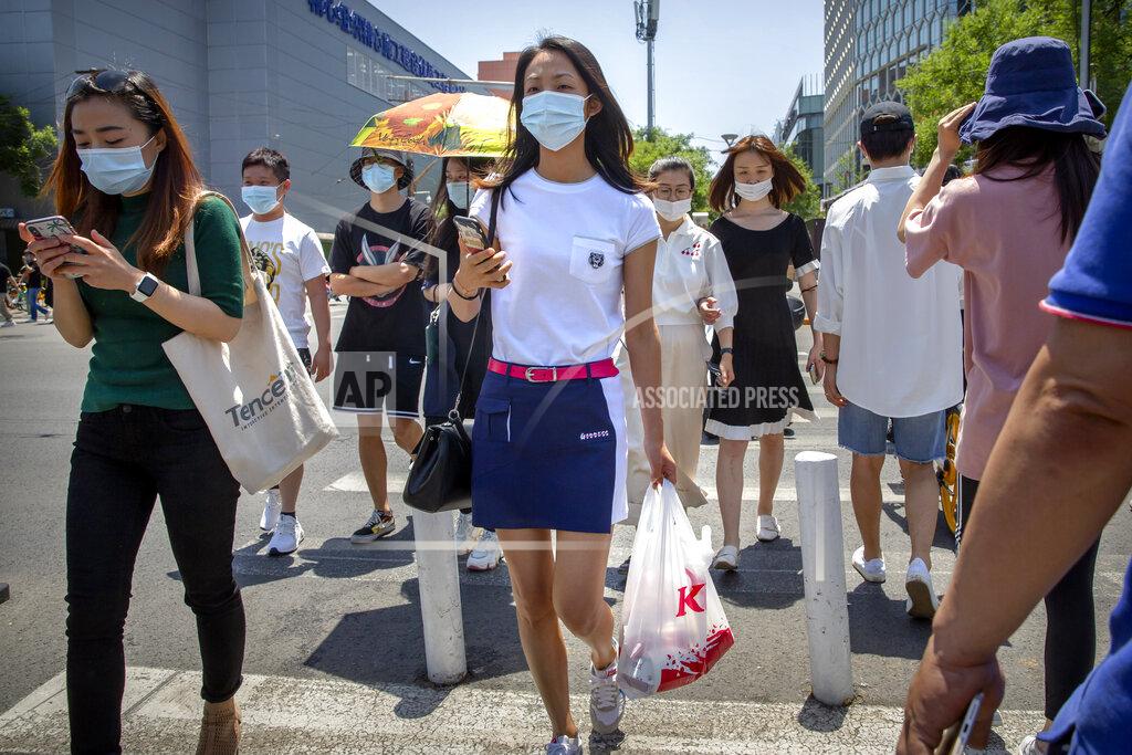 Mark Schiefelbein People wear face masks to protect against the coronavirus as they walk across an intersection in Beijing, Friday, June 5, 2020. China on Friday reported five new confirmed coronavirus cases, all of them brought by Chinese citizens from outside the country. (AP Photo/Mark Schiefelbein)